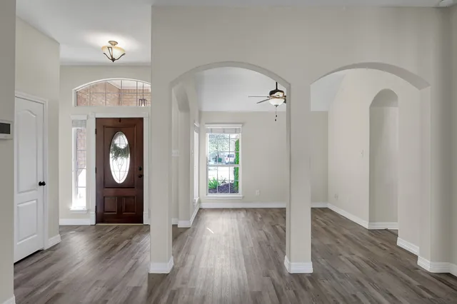 an empty room with wooden floor mirror and windows