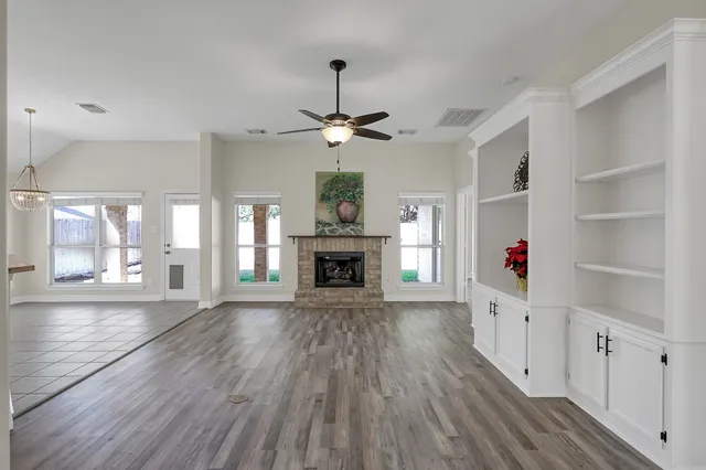 a view of a livingroom with wooden floor a fireplace and windows