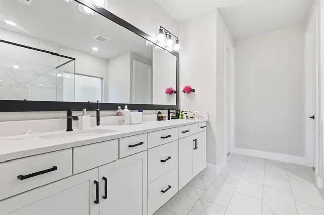 a bathroom with a double vanity sink a mirror and a bathtub