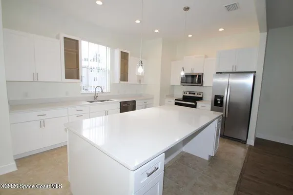 a kitchen with kitchen island a sink stainless steel appliances and white cabinets