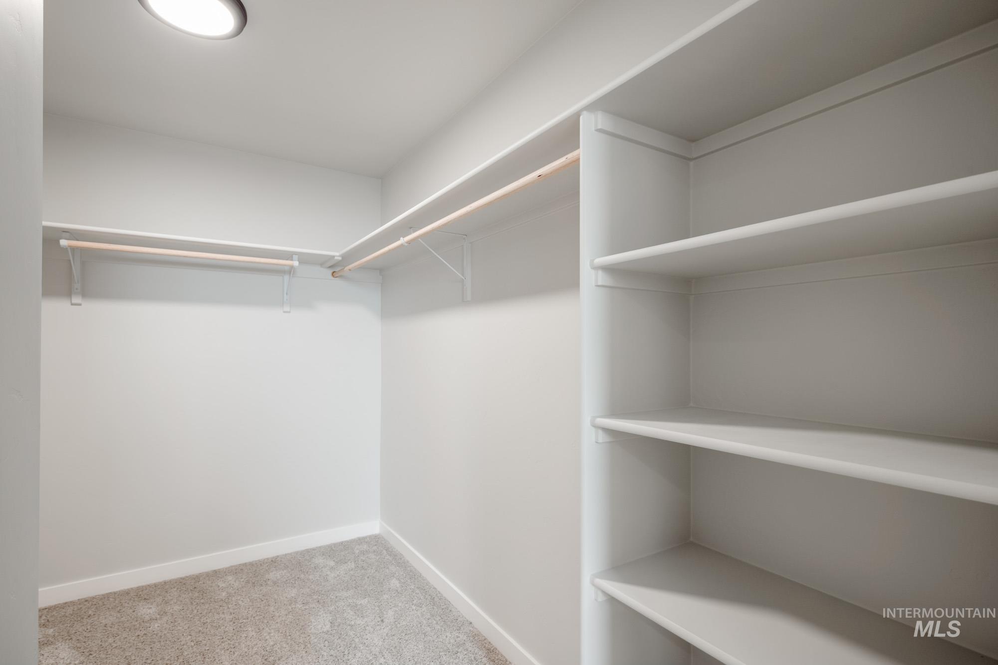 2391 West Fallon Loop Nampa, ID 83651 - Photo 19 of 20 Walk-in closet featuring built-in shelving, two hanging rods, plush carpet flooring, and recessed overhead lighting
