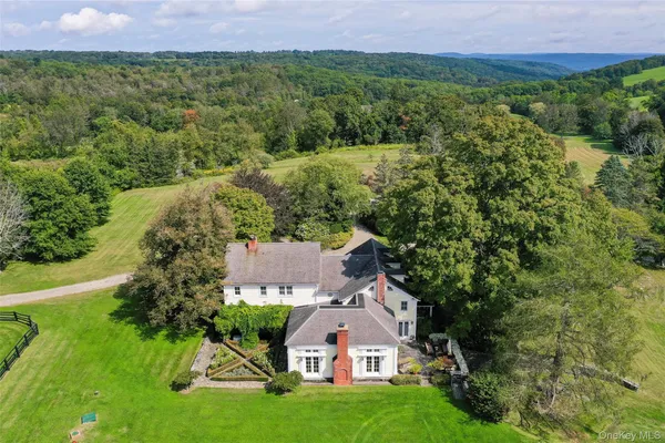 a view of a big house with a big yard and large trees