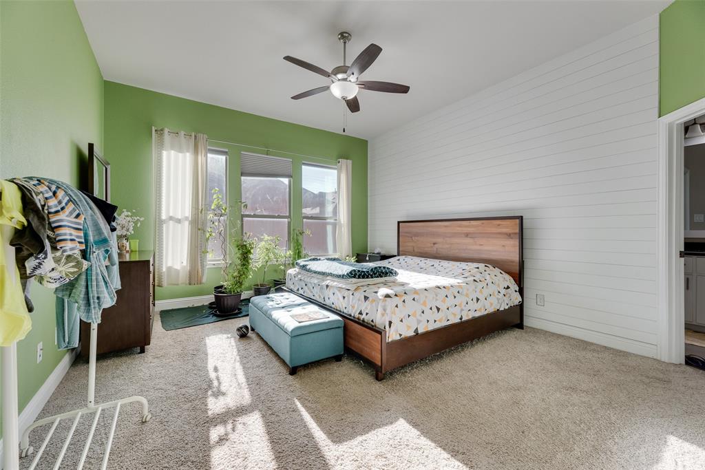 14809 Cedar Flt Way Fort Worth, TX 76262 - Photo 13 of 18 Bedroom featuring carpet, wooden walls, a ceiling fan, and an accent wall
