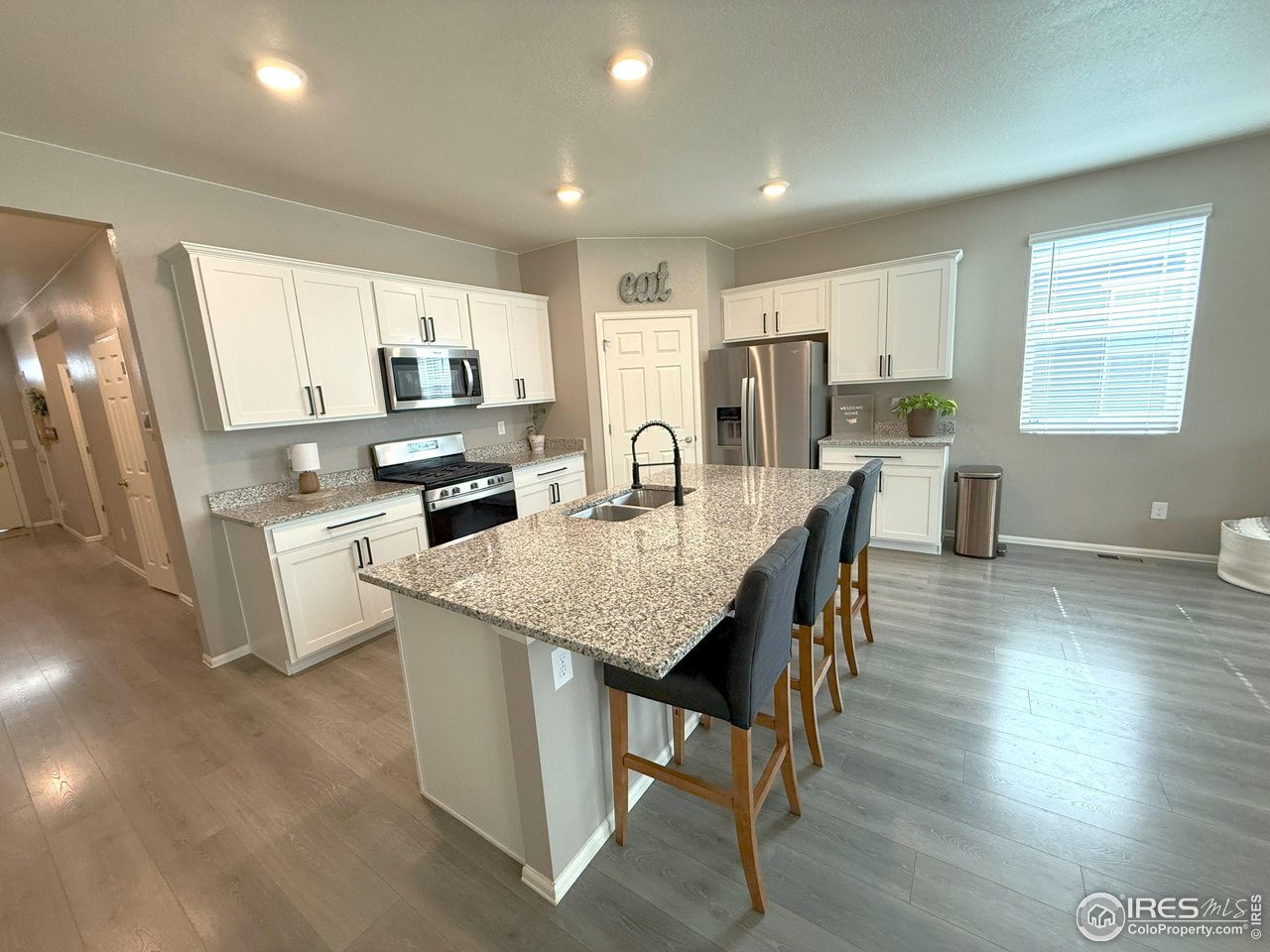 1780 Floret Drive Windsor, CO 80550 - Photo 6 of 36 a kitchen with stainless steel appliances granite countertop a stove a refrigerator a sink a dining table and chairs