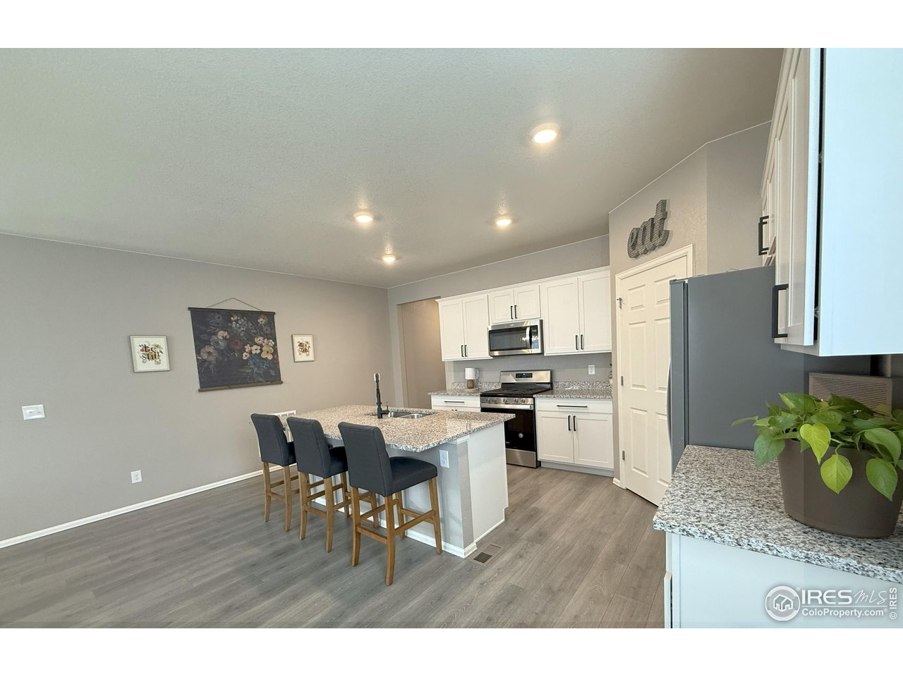 1780 Floret Drive Windsor, CO 80550 - Photo 9 of 36 a kitchen with stainless steel appliances kitchen island granite countertop a dining table chairs and granite counter tops