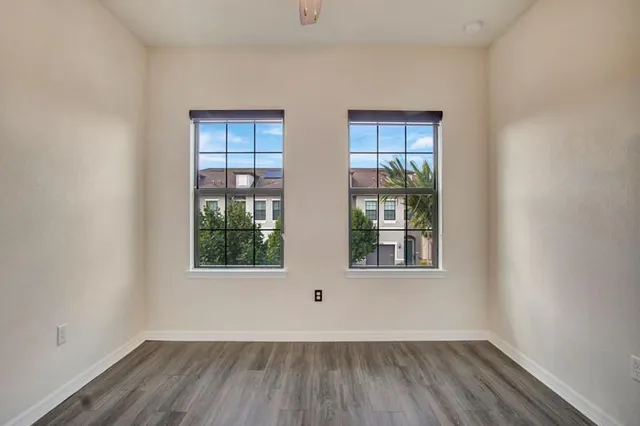 an empty room with wooden floor and windows