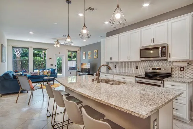 a kitchen with stainless steel appliances granite countertop a stove top oven a sink a dining table and chairs with wooden floor