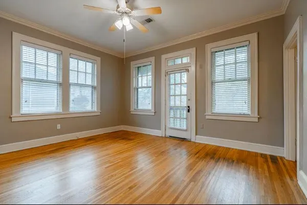 a view of an empty room with wooden floor and a window