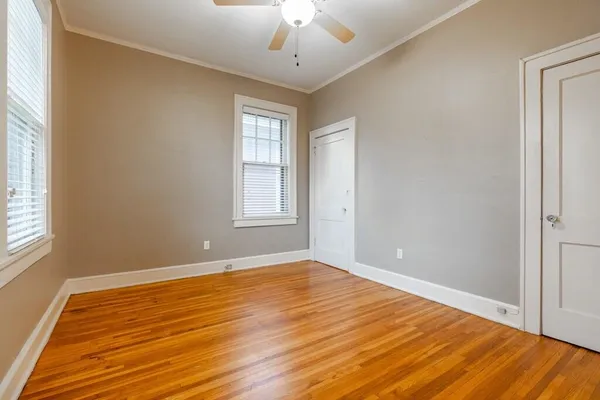 a view of empty room with wooden floor and fan