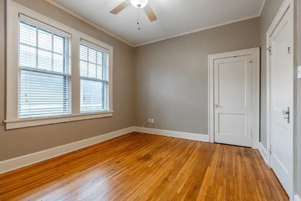 a view of empty room with wooden floor and fan