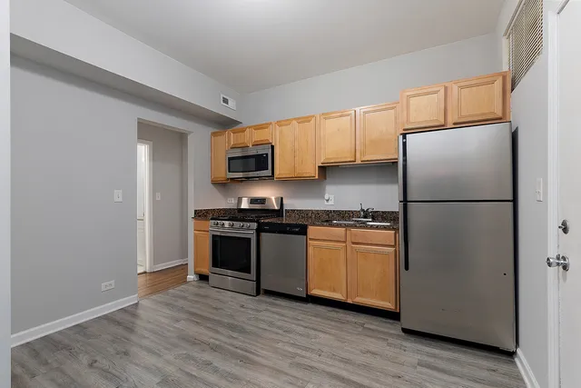 a kitchen with stainless steel appliances granite countertop a refrigerator stove a sink and dishwasher with wooden floor