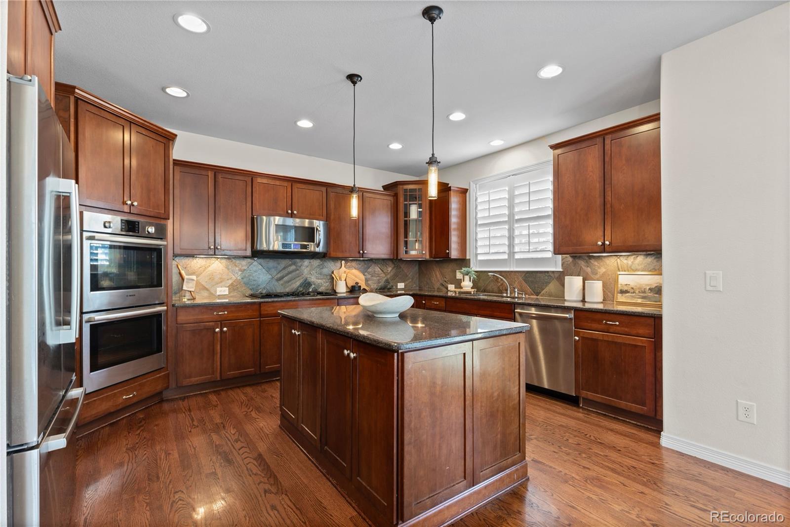 10840 Valleybrook Circle Highlands Ranch, CO 80130 - Photo 21 of 49 a kitchen with stainless steel appliances granite countertop wooden cabinets a sink dishwasher a stove and a refrigerator