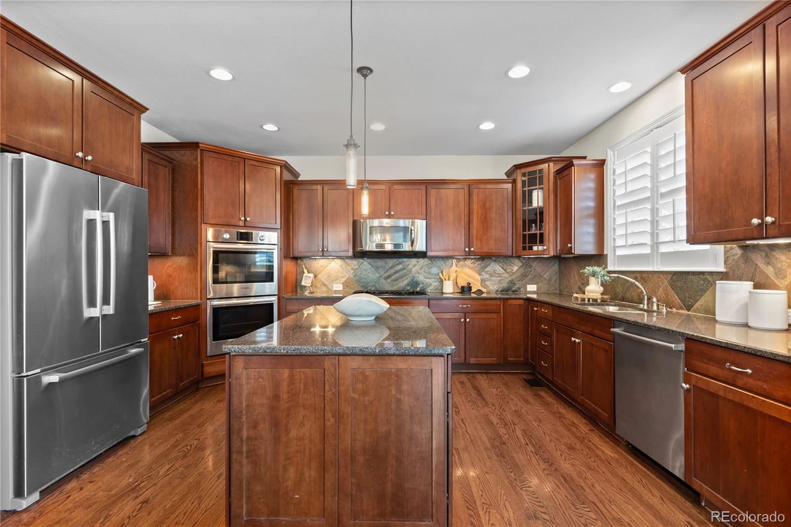 10840 Valleybrook Circle Highlands Ranch, CO 80130 - Photo 22 of 49 a large kitchen with stainless steel appliances granite countertop a refrigerator a sink dishwasher a oven with wooden cabinets and floor