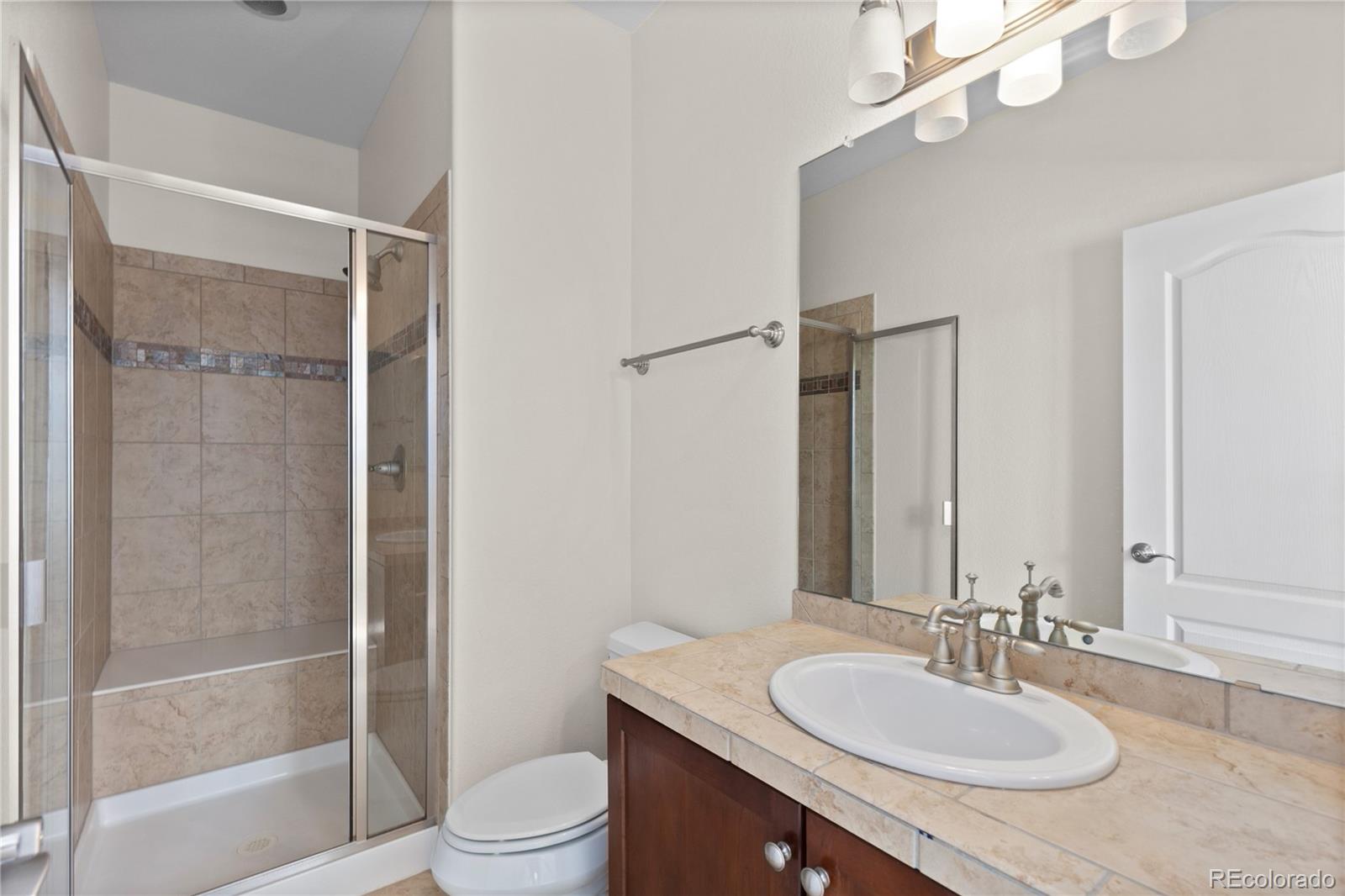 10840 Valleybrook Circle Highlands Ranch, CO 80130 - Photo 7 of 49 a bathroom with a granite countertop sink toilet a mirror and shower