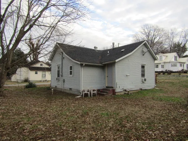 a view of a house with a yard and a large tree