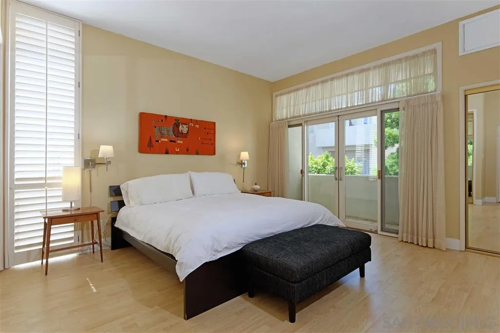 1228 Cave Street La Jolla, CA 92037 - Photo 16 of 22 a bedroom with a bed lamp and a large window