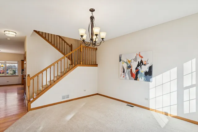 a view of a hallway to a livingroom with wooden floor and stairs