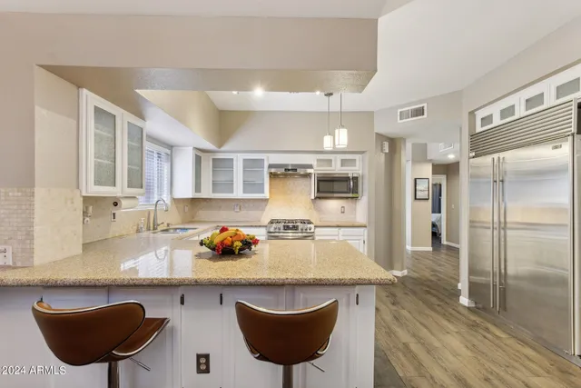 a kitchen with stainless steel appliances granite countertop a sink and a refrigerator