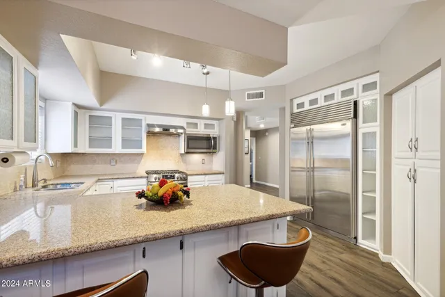 a kitchen with granite countertop a sink cabinets and stainless steel appliances
