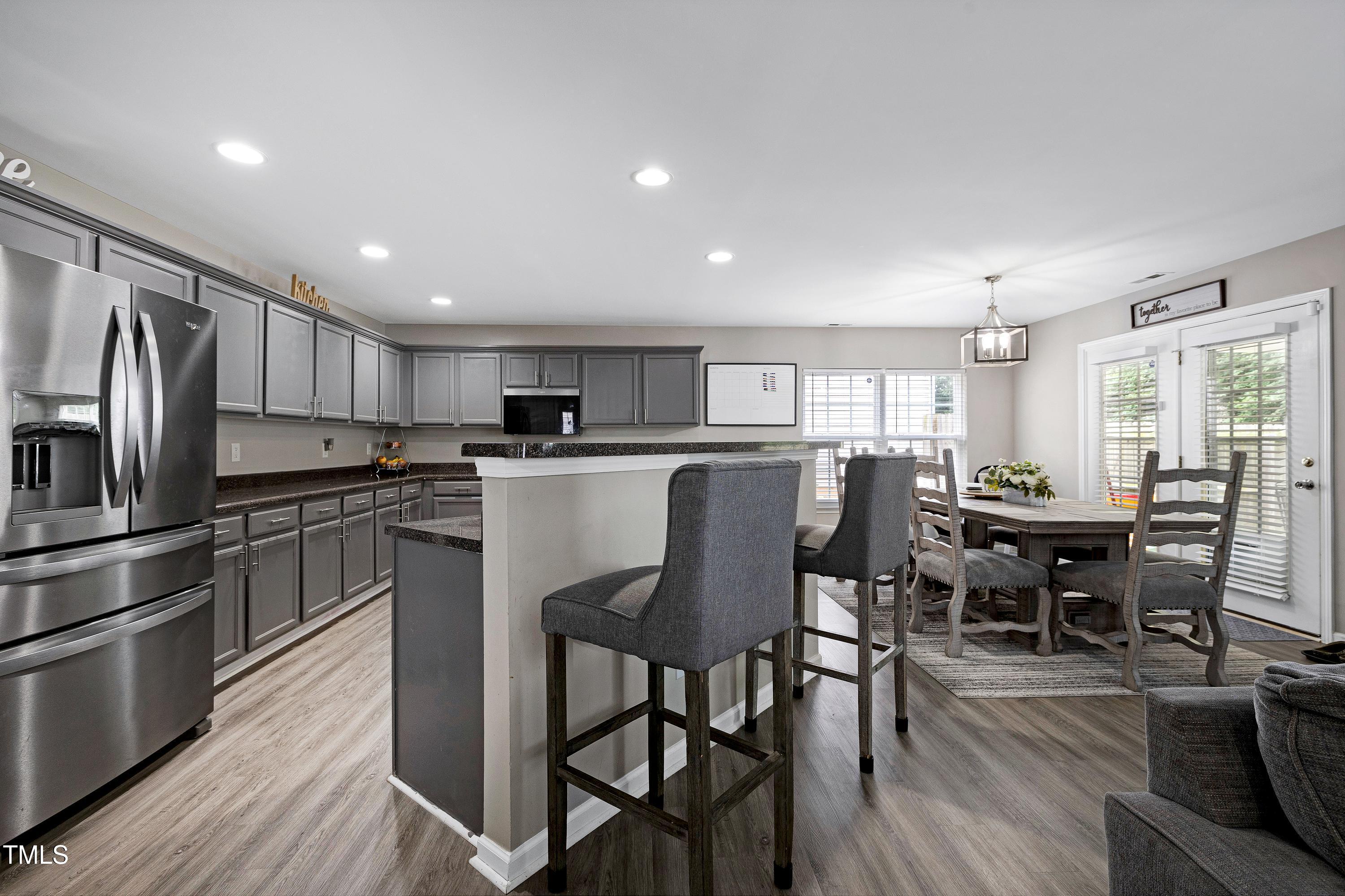 5428 Meryton Park Way Raleigh, NC 27616 - Photo 8 of 29 a kitchen with a dining table chairs refrigerator and cabinets