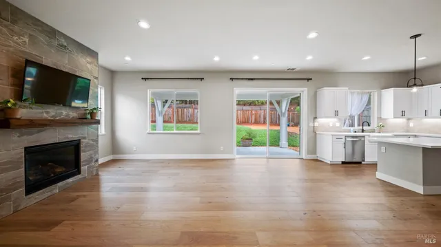 a living room with stainless steel appliances furniture a flat screen tv and a fireplace