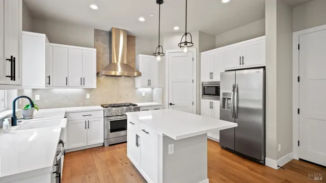 a kitchen with stainless steel appliances a refrigerator sink and wooden floor