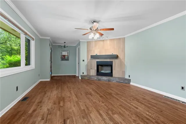 a view of empty room with wooden floor and fan