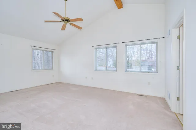 an empty room with a chandelier fan and windows