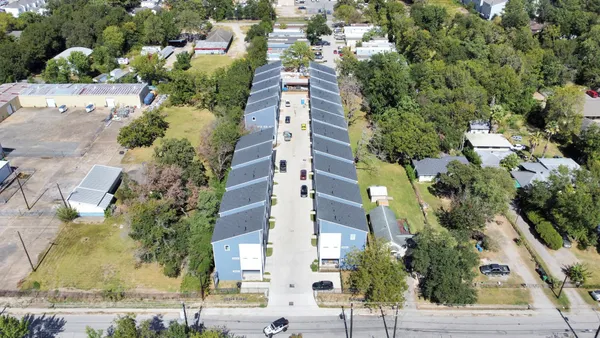 an aerial view of a residential apartment building with a yard and parking spaces