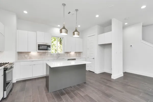 a large kitchen with granite countertop a sink a counter space appliances and cabinets