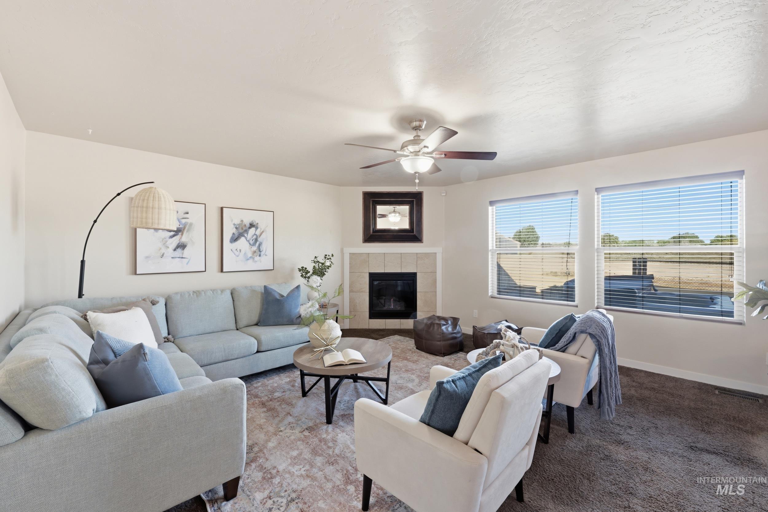 4855 South Chex Way Boise, ID 83709 - Photo 8 of 47 Living area featuring a corner fireplace with tile surround, multiple windows, a ceiling fan, and carpet flooring