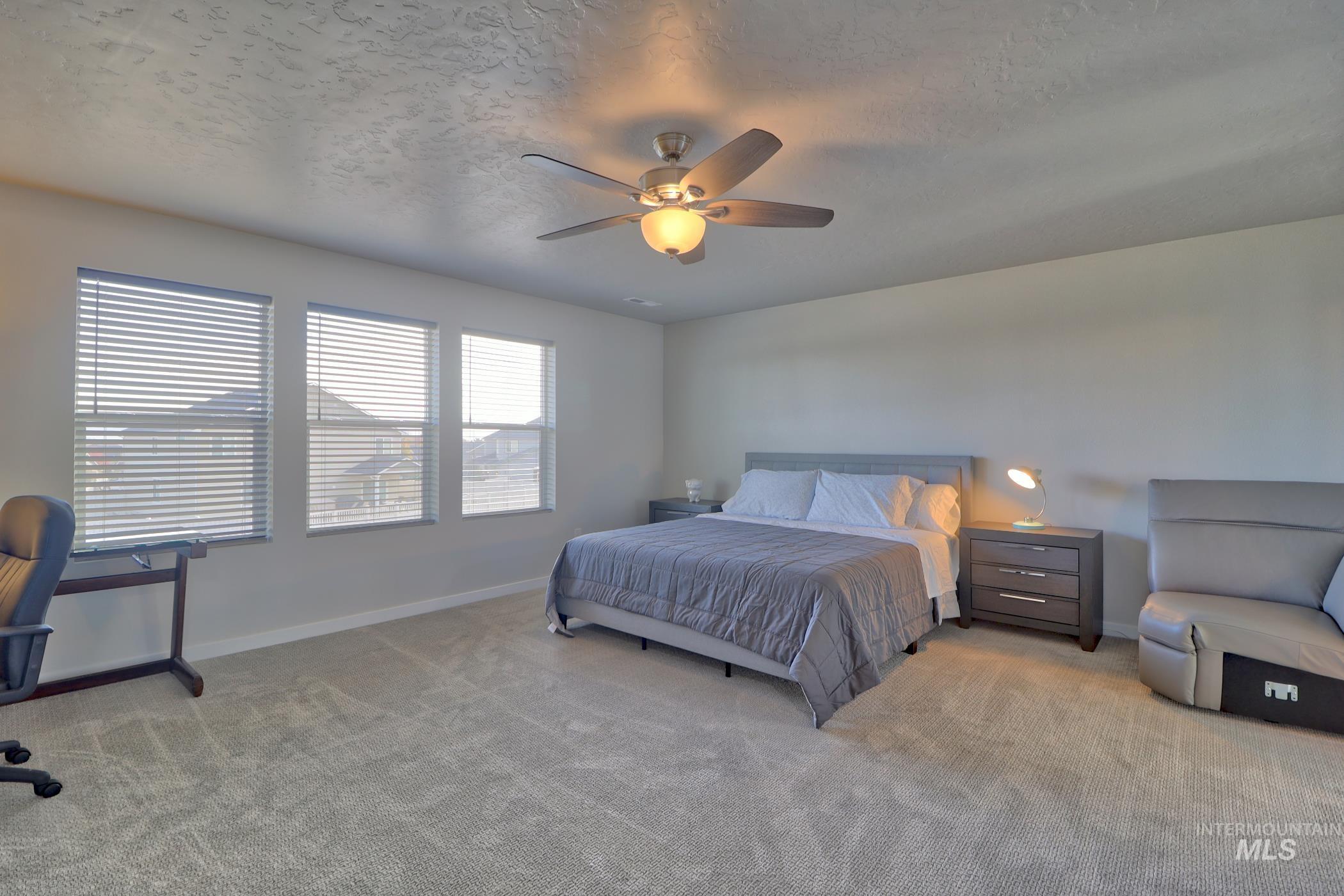 3508 South Edge Rim Way Meridian, ID 83642 - Photo 20 of 28 Spacious room featuring three windows with horizontal blinds, neutral carpeting, and a ceiling fan with integrated lighting