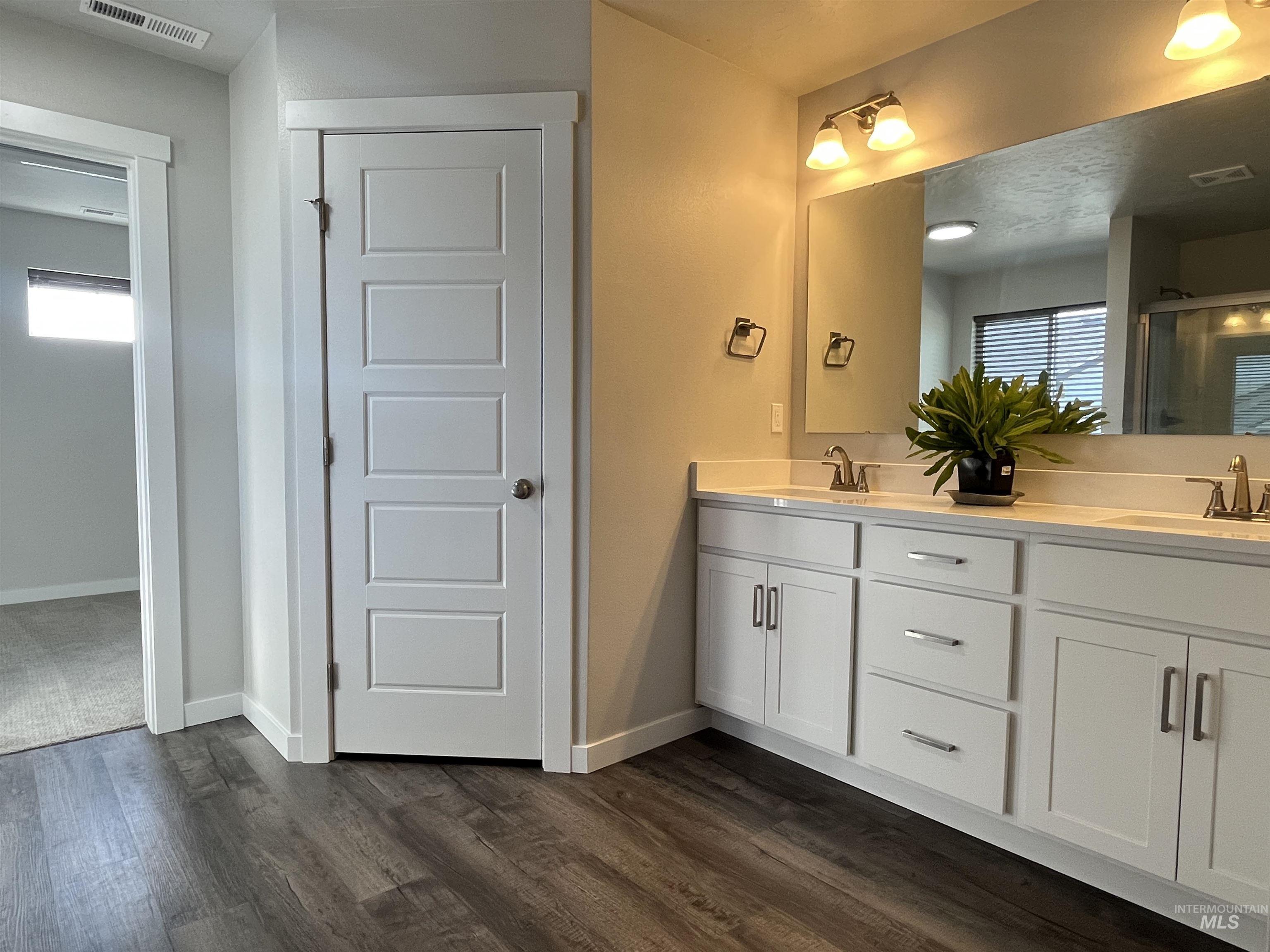 3508 South Edge Rim Way Meridian, ID 83642 - Photo 24 of 28 Double vanity with white cabinetry, integrated sinks, chrome fixtures, and a large wall-mounted mirror