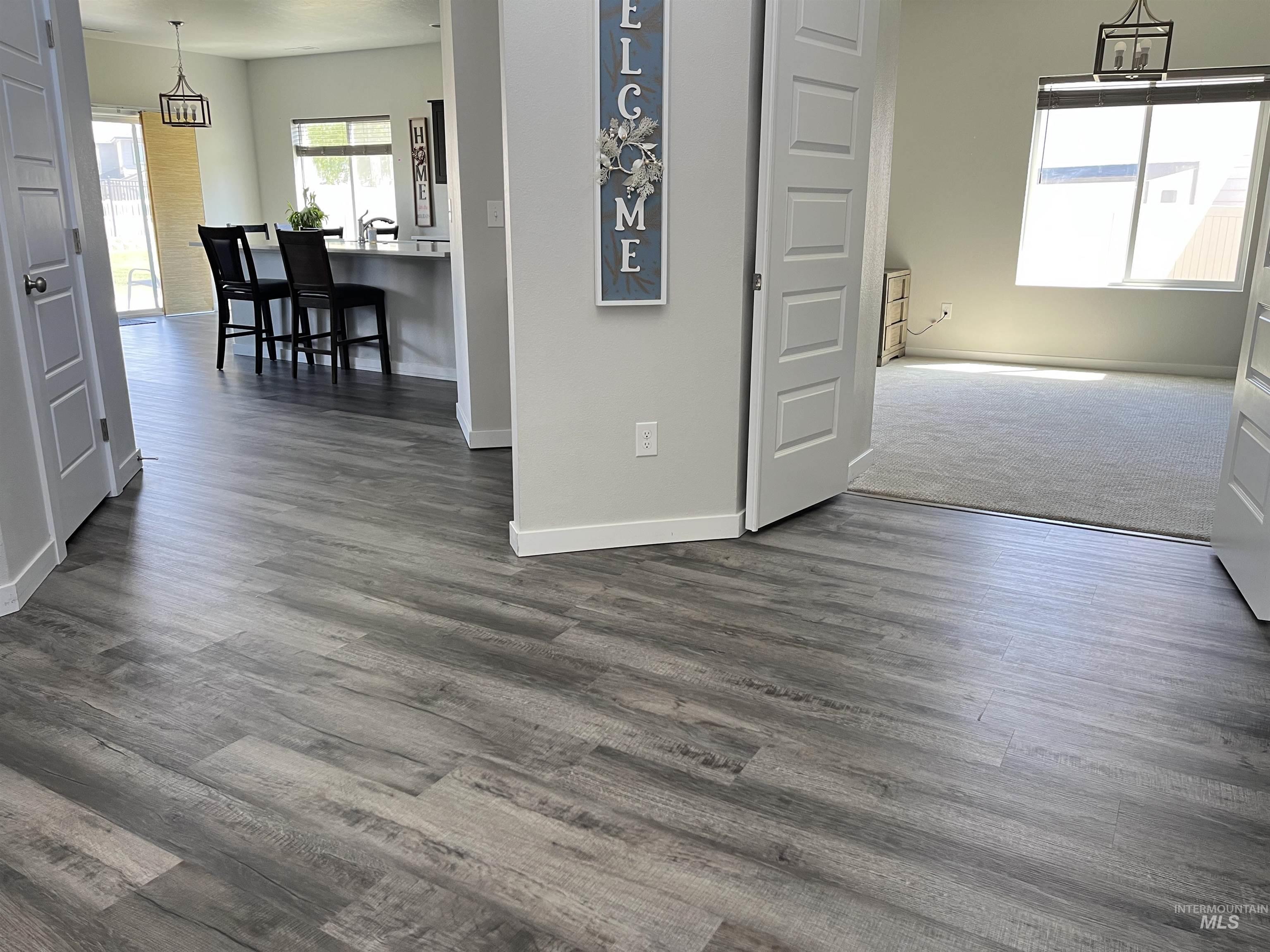 3508 South Edge Rim Way Meridian, ID 83642 - Photo 4 of 28 Spacious interior featuring wood-finish flooring, a kitchen island with sink, and white baseboards