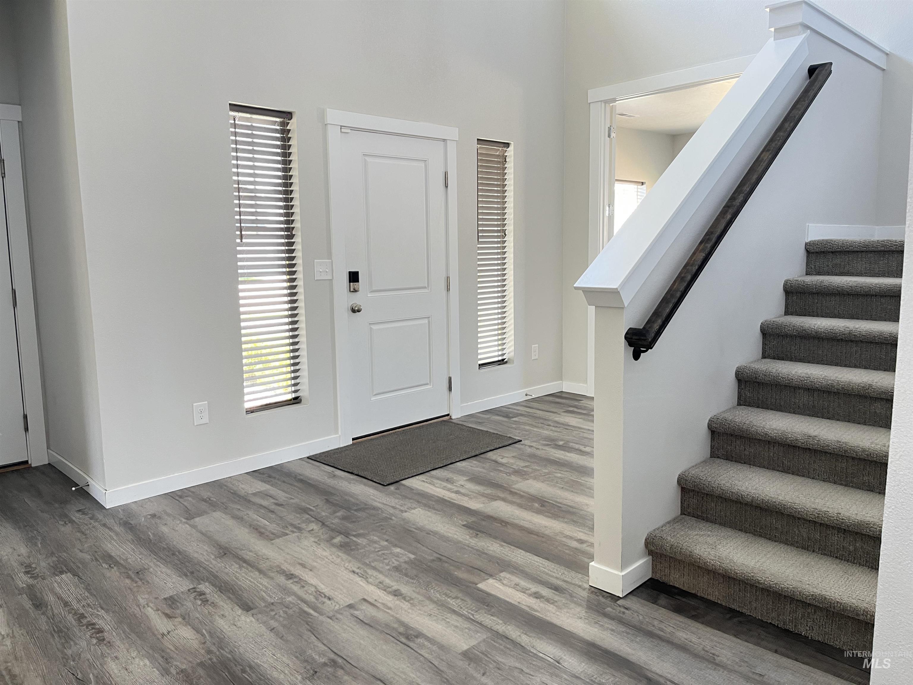 3508 South Edge Rim Way Meridian, ID 83642 - Photo 5 of 28 Entryway featuring wood-finish flooring and a carpeted staircase with a dark-toned handrail
