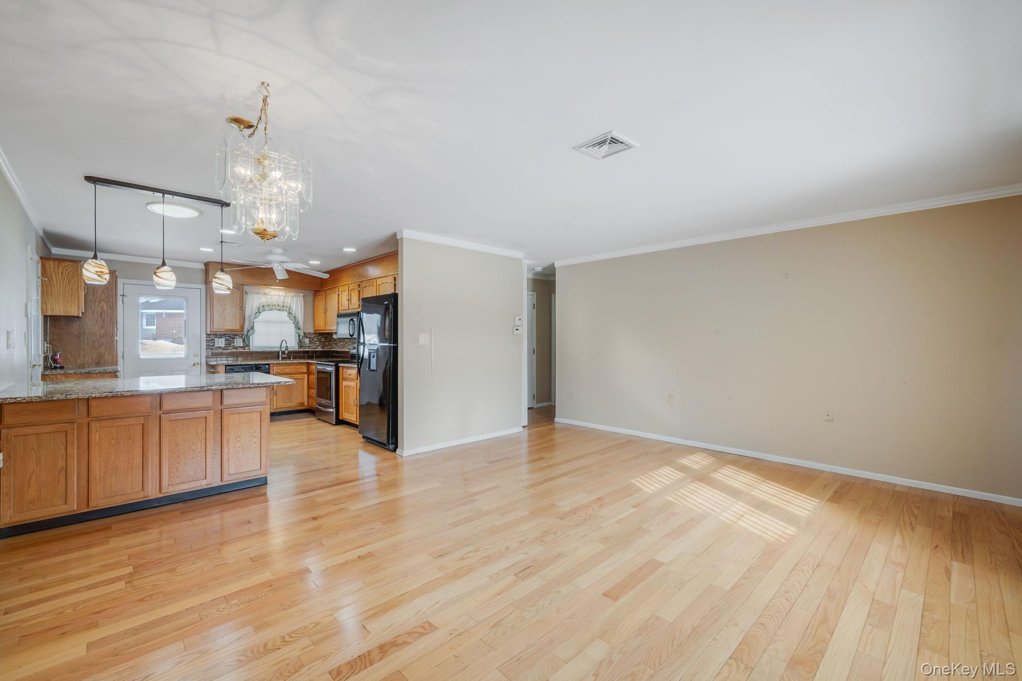 61 Enfield Court, Unit B Ridge, NY 11961 - Photo 12 of 32 a view of a kitchen with kitchen island granite countertop wooden floor and stainless steel appliances
