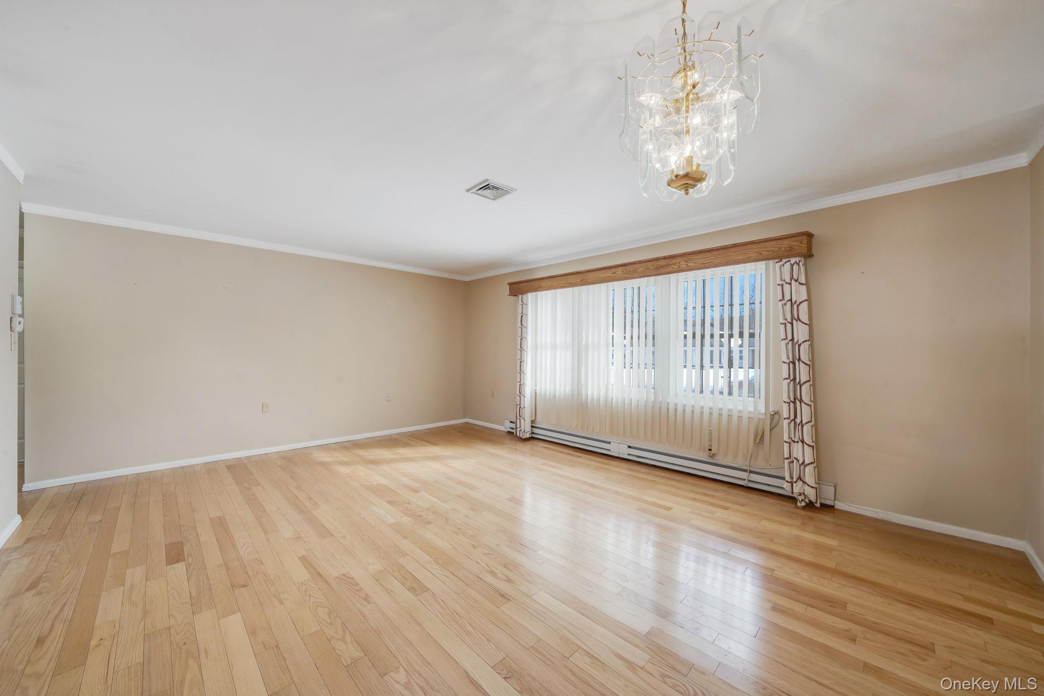 61 Enfield Court, Unit B Ridge, NY 11961 - Photo 13 of 32 a view of an empty room with wooden floor and a window