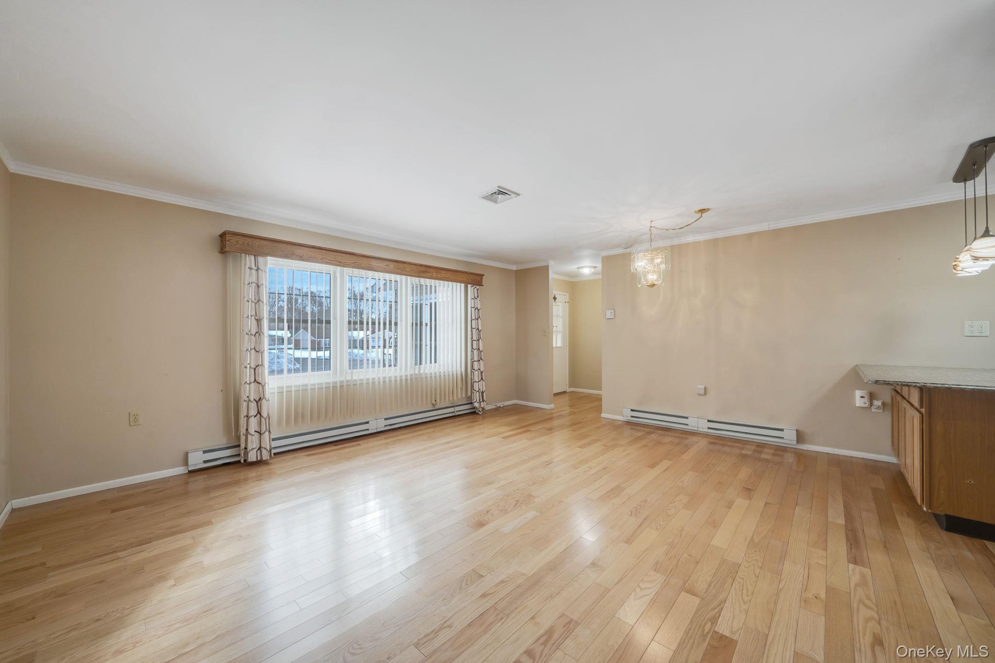 61 Enfield Court, Unit B Ridge, NY 11961 - Photo 17 of 32 a view of an empty room with wooden floor and a window