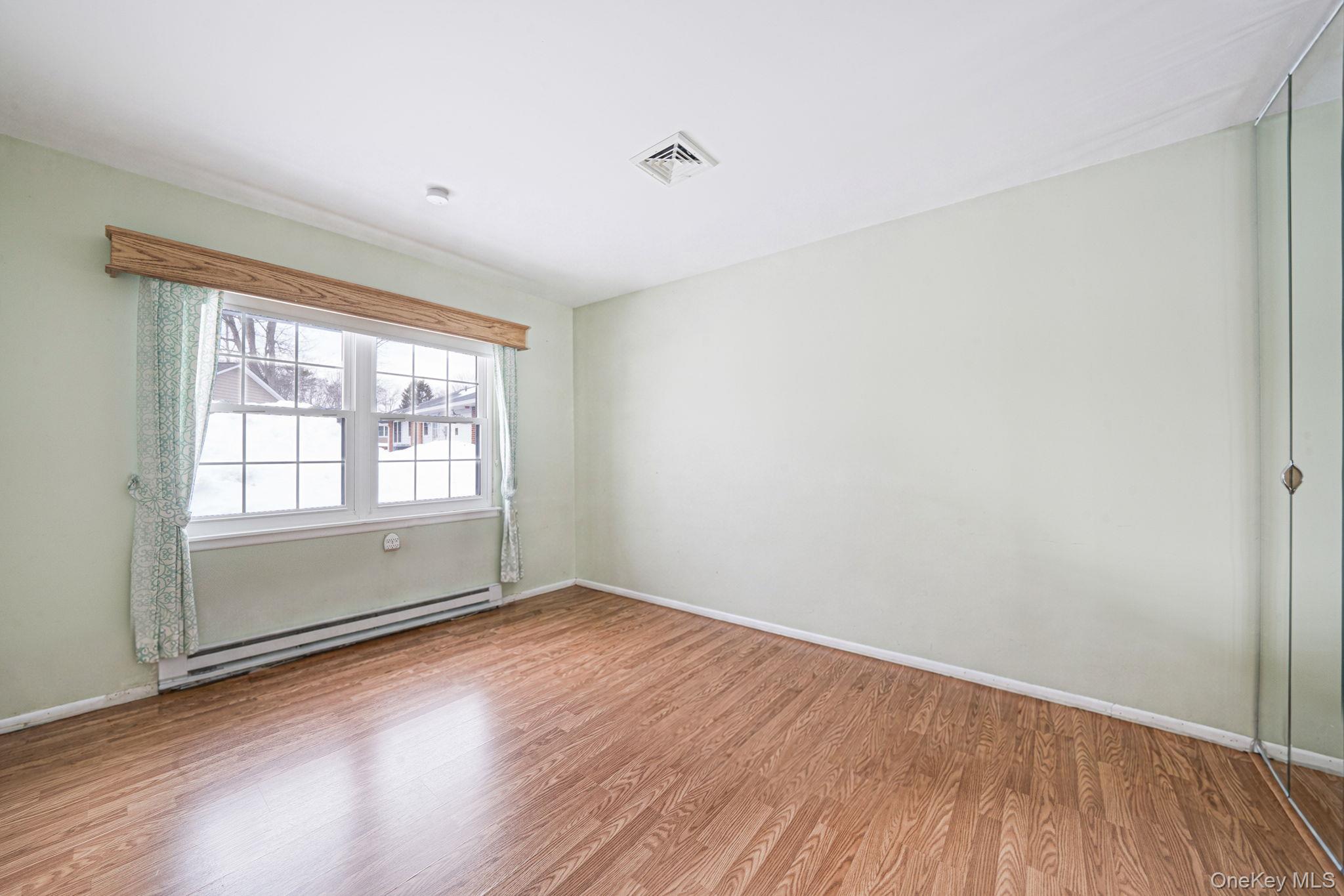 61 Enfield Court, Unit B Ridge, NY 11961 - Photo 25 of 32 an empty room with wooden floor and windows
