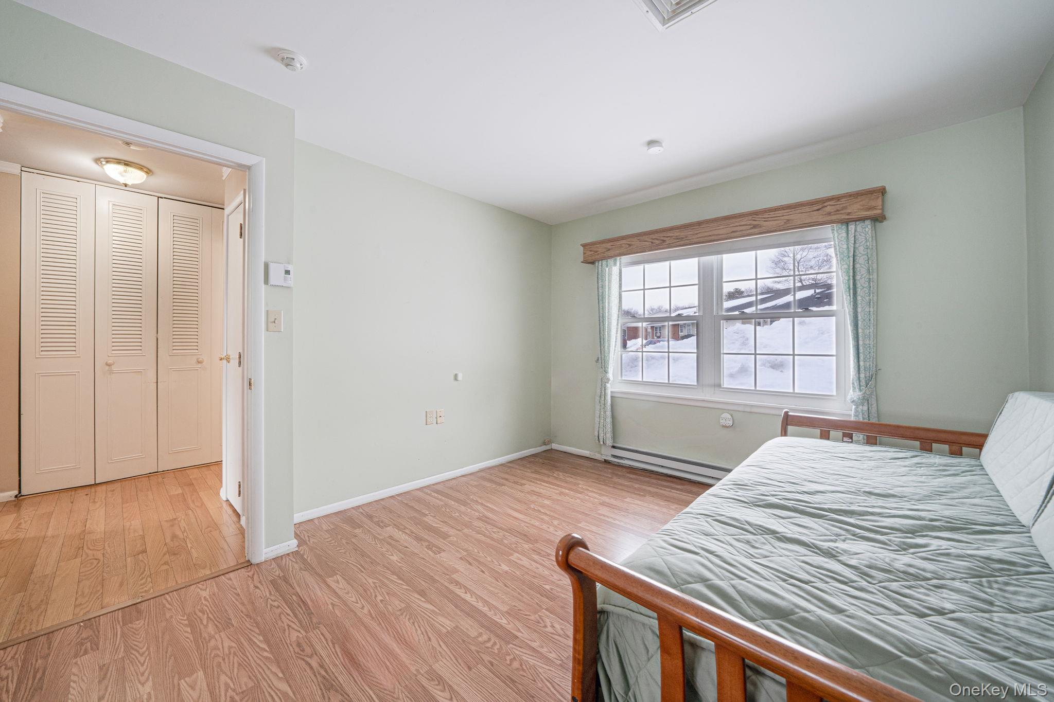 61 Enfield Court, Unit B Ridge, NY 11961 - Photo 27 of 32 a bedroom with a bed and a window