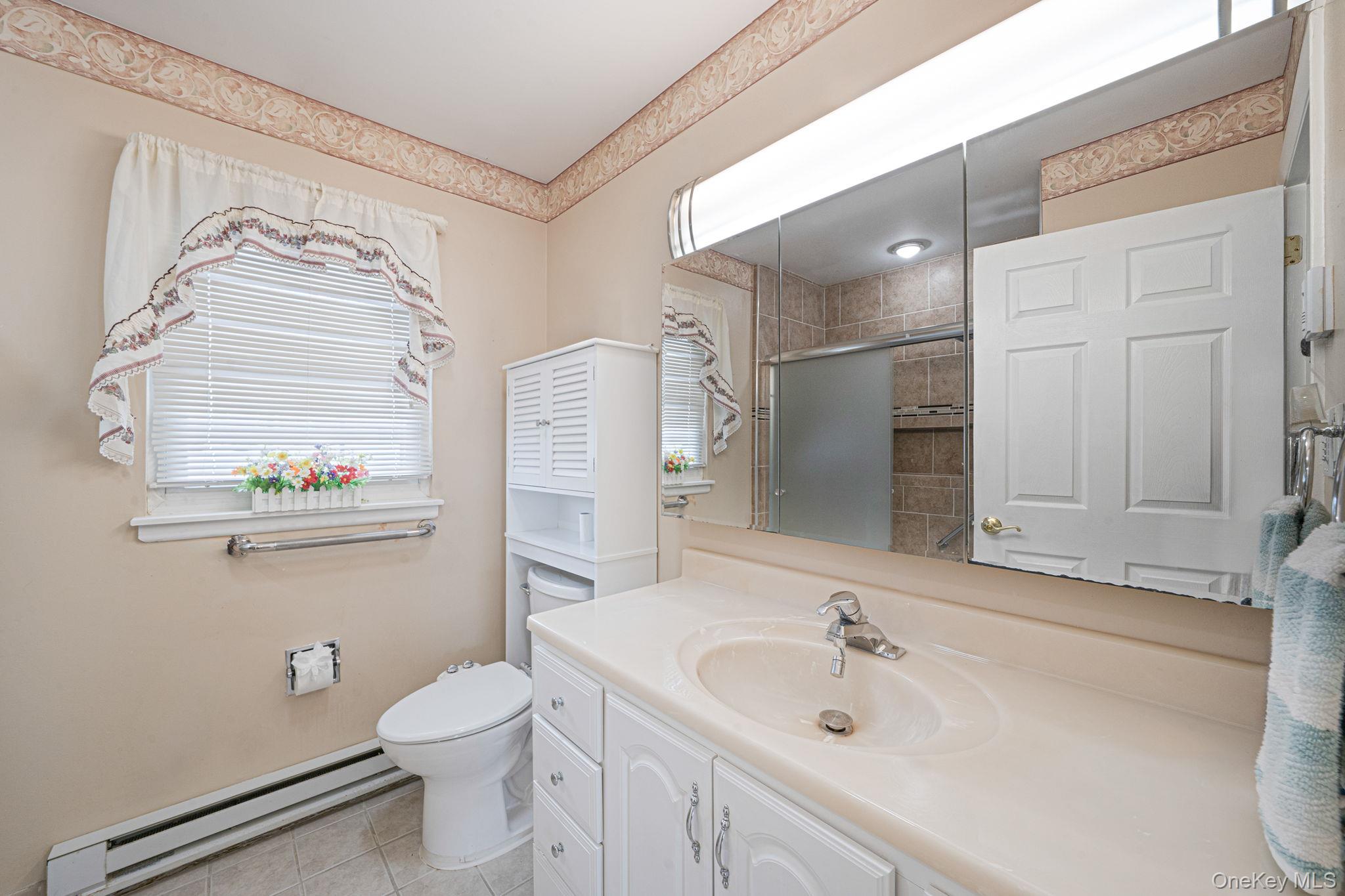 61 Enfield Court, Unit B Ridge, NY 11961 - Photo 28 of 32 a bathroom with a sink a toilet and a shower curtain