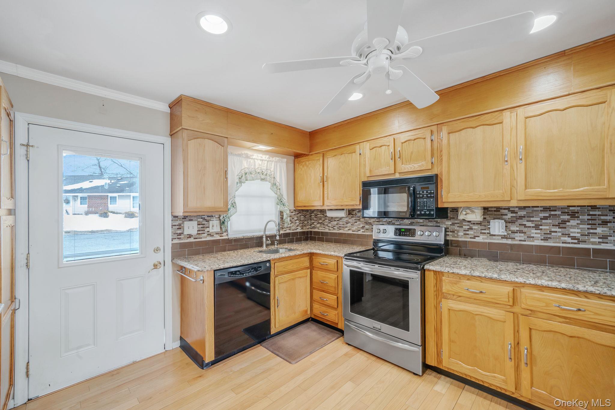 61 Enfield Court, Unit B Ridge, NY 11961 - Photo 8 of 32 a kitchen with stainless steel appliances granite countertop a stove sink and cabinets
