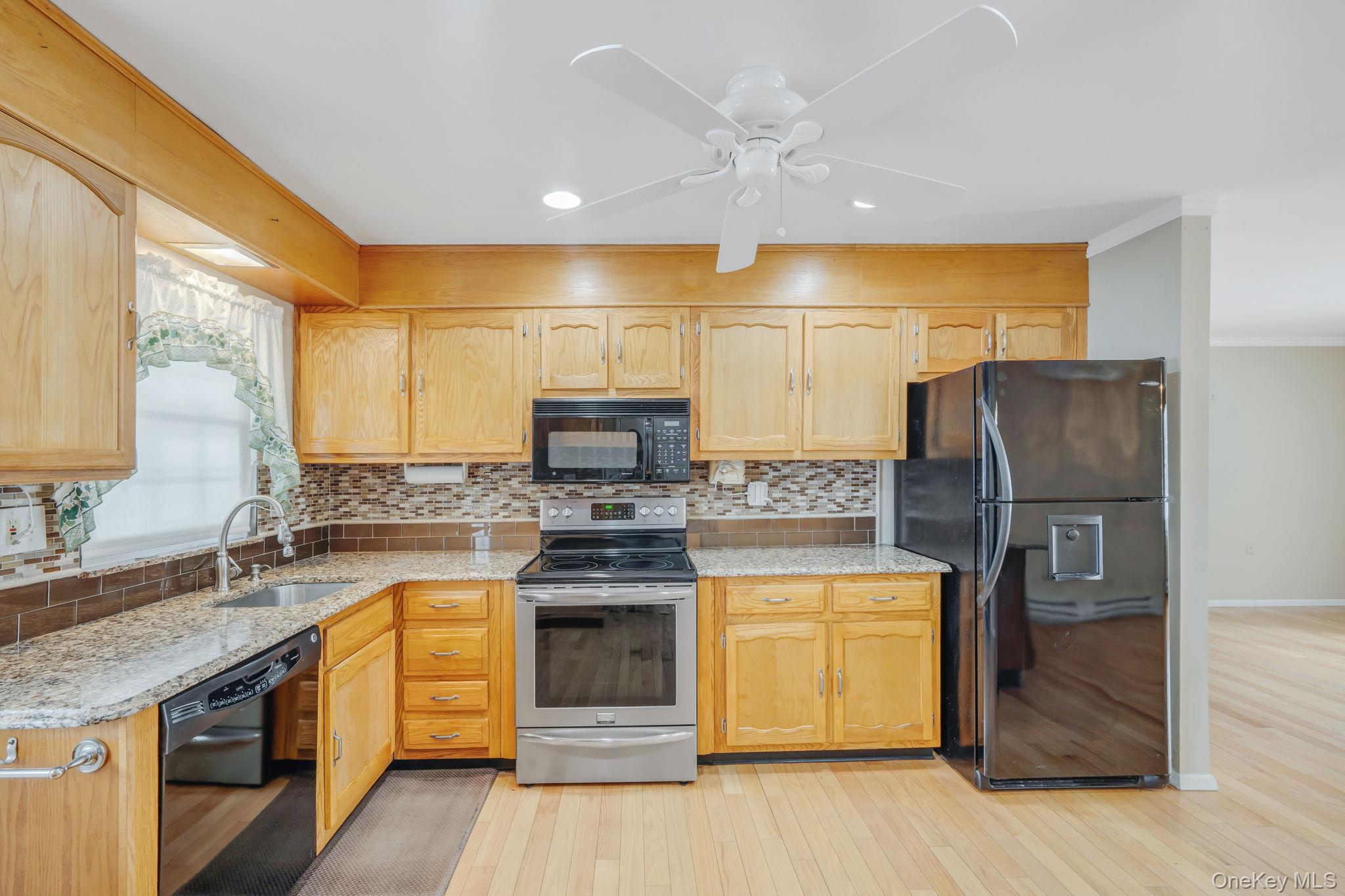 61 Enfield Court, Unit B Ridge, NY 11961 - Photo 9 of 32 a kitchen with stainless steel appliances granite countertop a sink a stove and a refrigerator