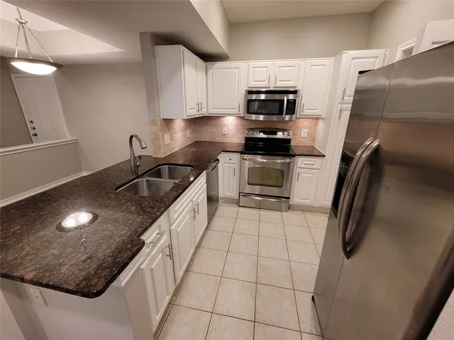 a kitchen with granite countertop a sink a stove and refrigerator