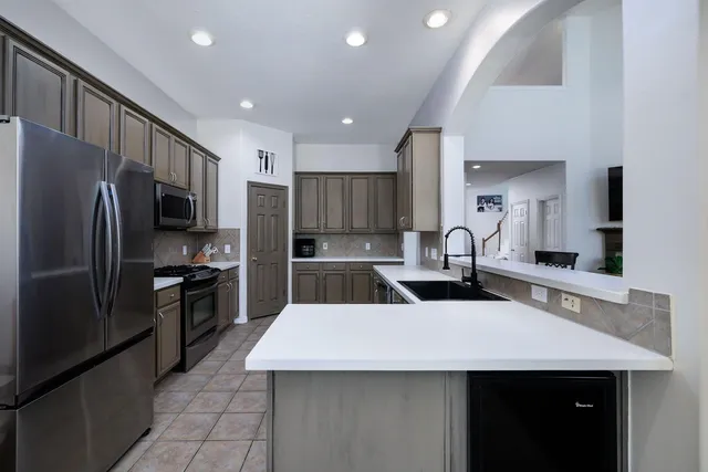 a kitchen with a sink a kitchen island stainless steel appliances cabinets and a counter top space