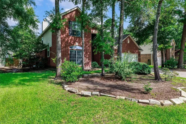 a view of a yard in front of a house with plants and large trees