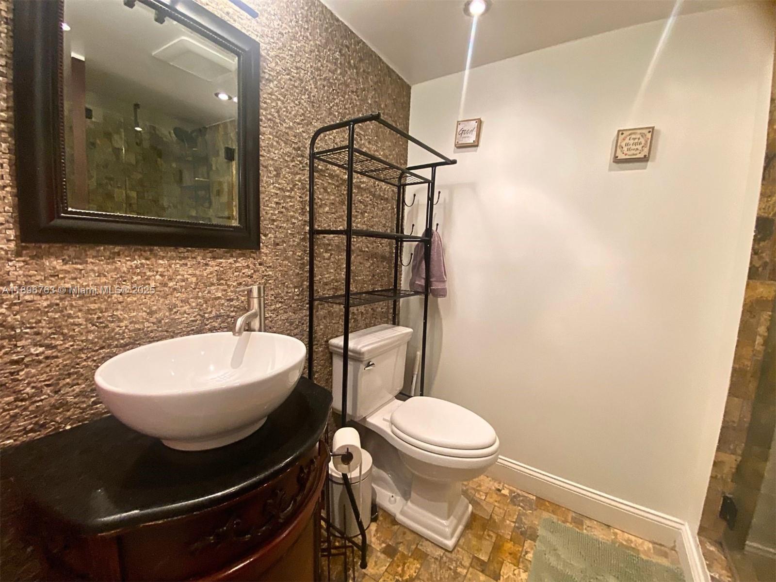 753 Michigan Avenue, Unit 2B Miami Beach, FL 33139 - Photo 13 of 22 a bathroom with a toilet sink and mirror