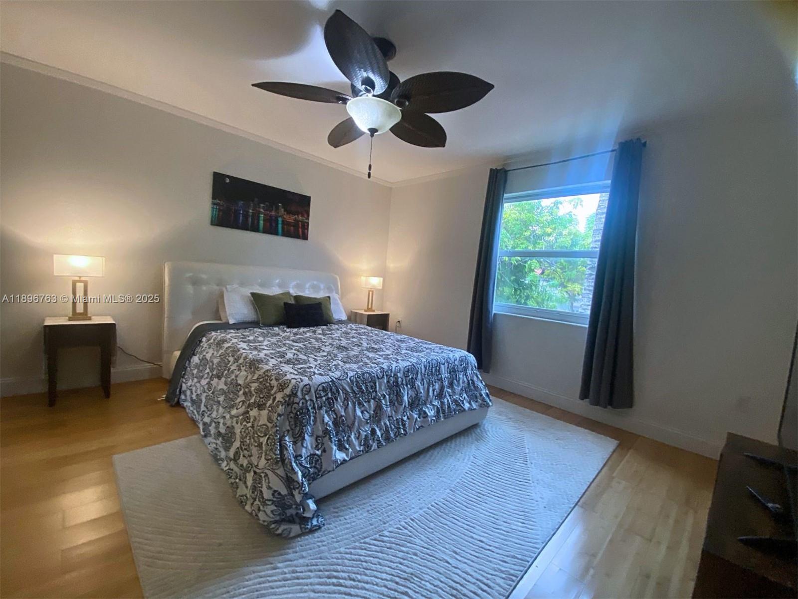 753 Michigan Avenue, Unit 2B Miami Beach, FL 33139 - Photo 16 of 22 a bedroom with a large bed chandelier and a window