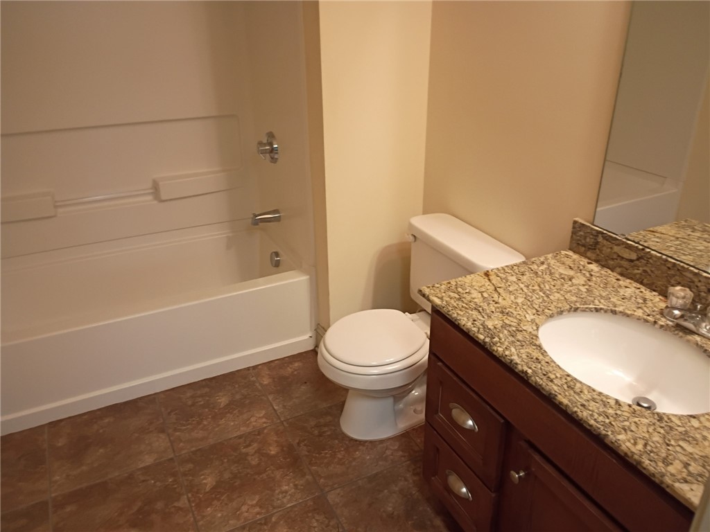 Rich granite countertops accent a classic wooden vanity set against durable tile flooring.