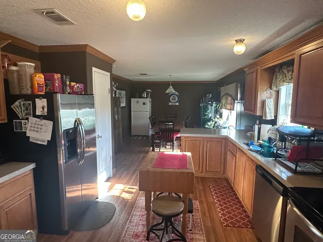 a kitchen with stainless steel appliances kitchen island granite countertop a refrigerator a stove top oven a sink and dishwasher